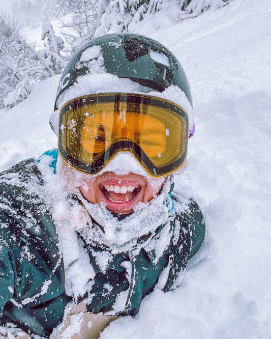 Pure Shred Goggles – smilende person med gul linse dekket av puddersnø