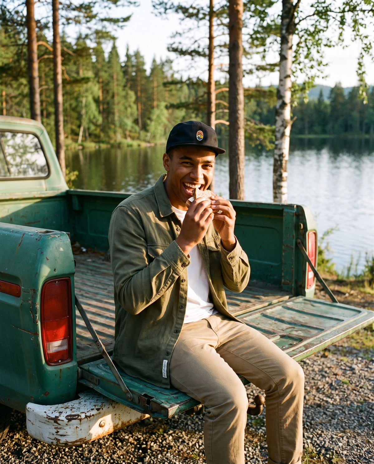 5 Panel Cap Classic – leende mann spiser matpakke på en pickup ved et skogsvann