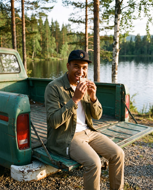 5 Panel Cap Classic – leende mann spiser matpakke på en pickup ved et skogsvann