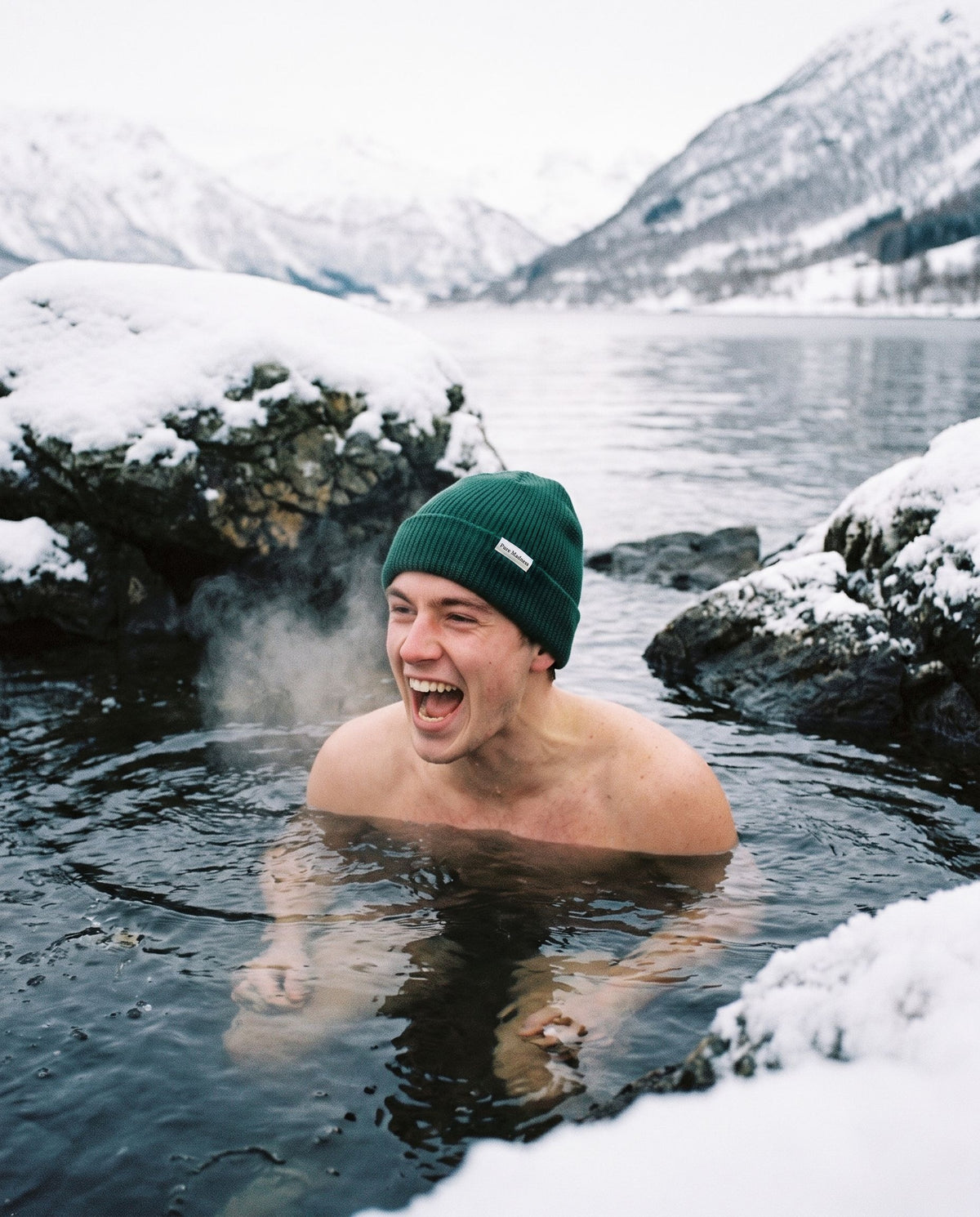 Green Captain Merino Beanie – leende mann tar isbad i en fjord med snø rundt