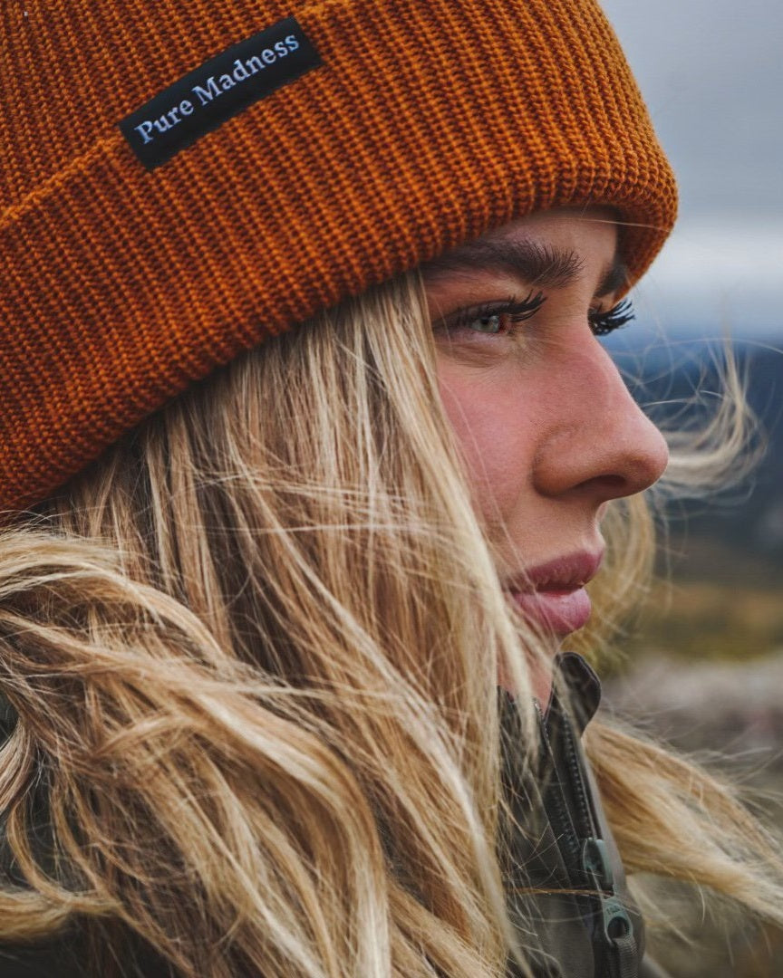 Orange Captain Merino Beanie – nærbilde av kvinne i profil med håret i vinden
