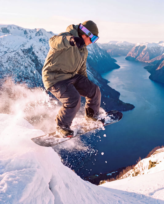 Pure Shred Goggles – snowboarder i luften med gogglesene over en fjord med snødekte fjell