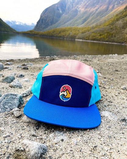 5 Panel Cap Ocean Sunset – capsen på en steinstrand ved en innsjø