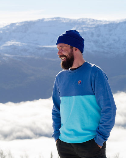 Blue Wave Crew Sweatshirt – smilende mann med blå lue i genseren over skylaget