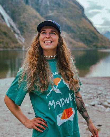 Join the Madness Teal Tee – kvinne med caps i turkis t-skjorte med «Join the Madness»-trykk ved et fjellvann