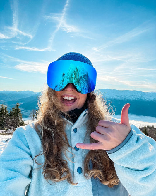 Pure Shred Goggles – kvinne med gogglesene gjør shaka-tegn på fjellet